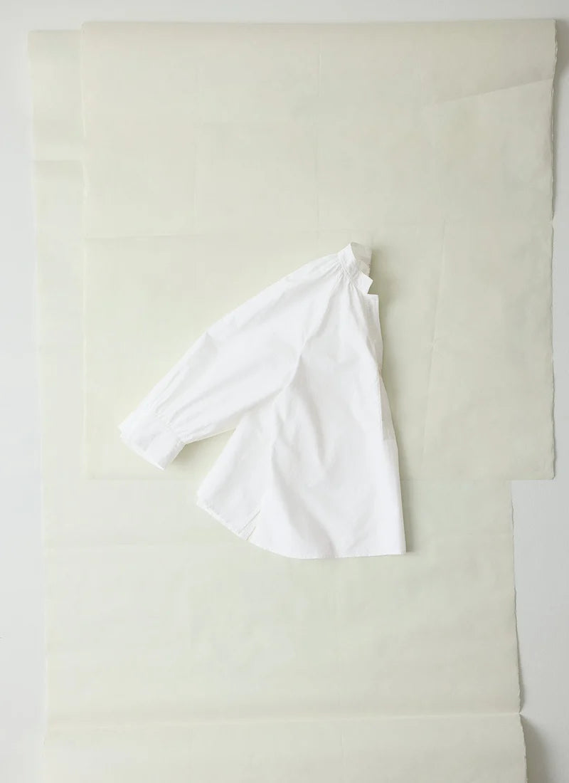 A photo of a white shirt shown laying flat and folded in half.