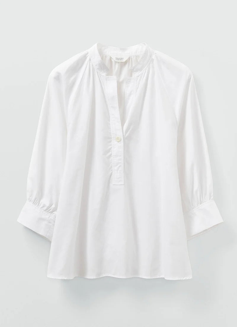 A white cotton oxford shirt shown laying flat.