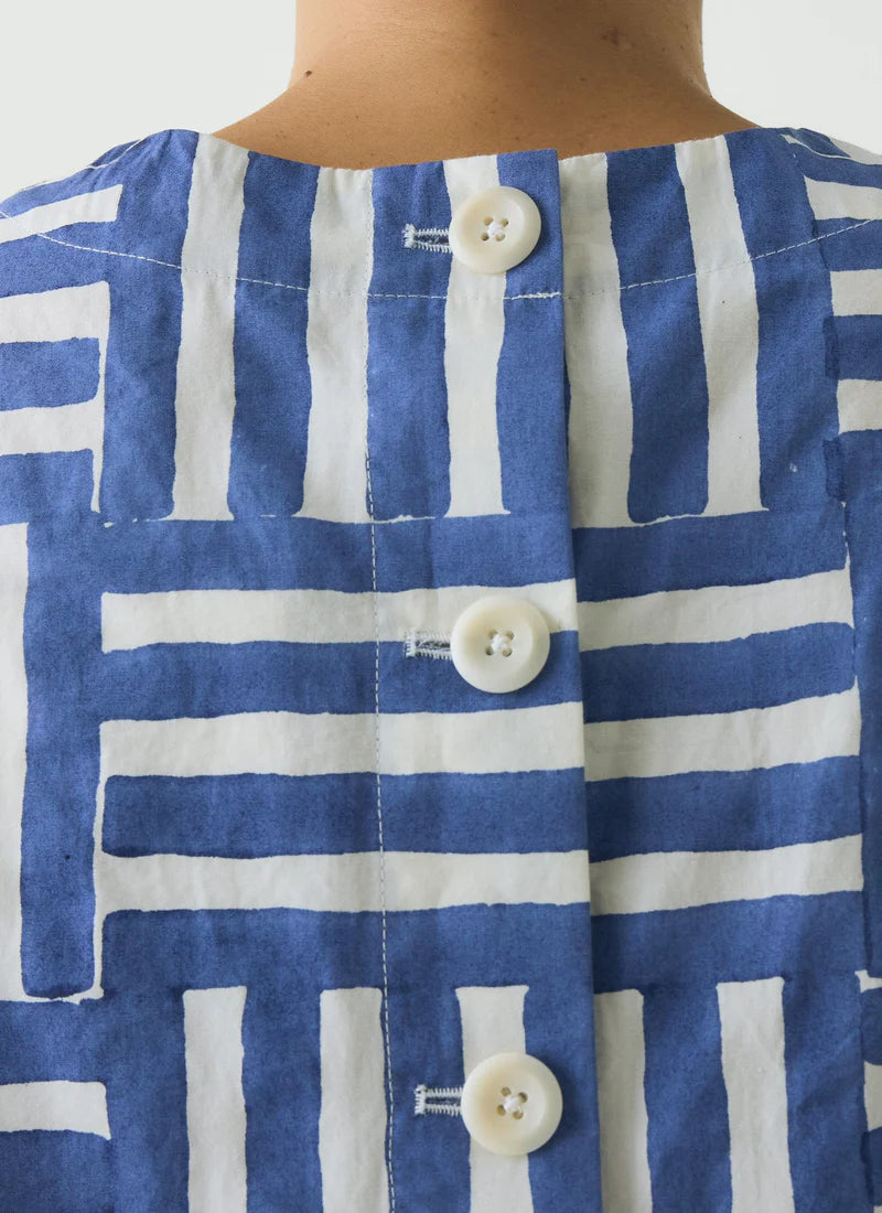 Detail of back button closure on person wearing blue and white top against a white backround