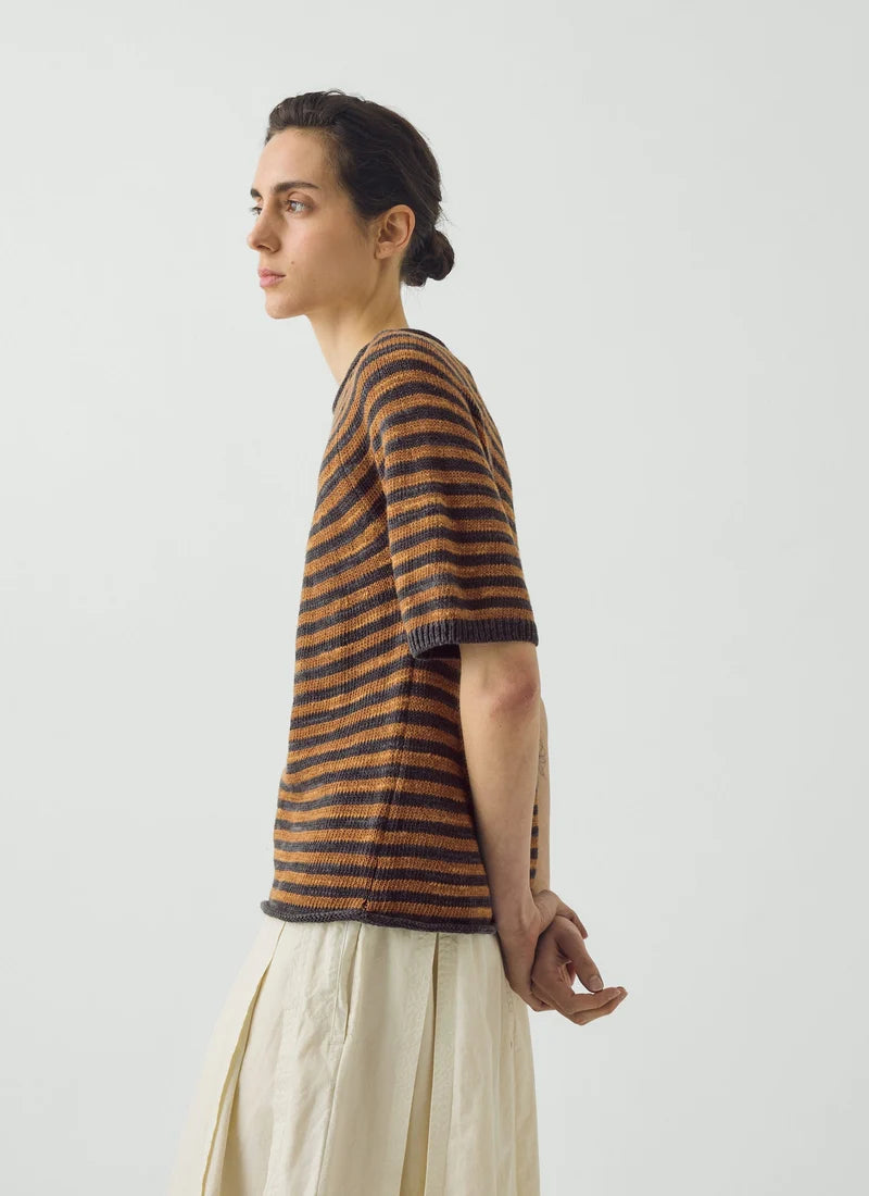 A model shown wearing a soft copper and graphite blue striped knitted and white pants.