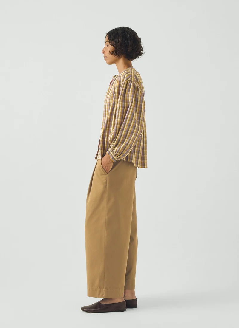A photo of a model wearing a check top with yellows, greens, and purples.