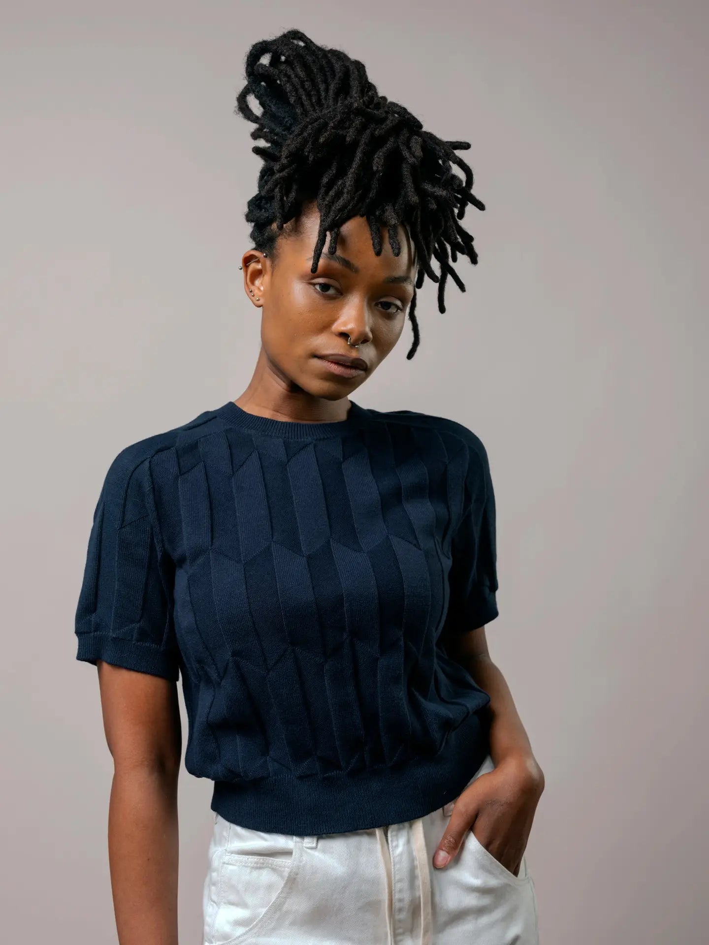Woman wearing a dark blue textured top against a plain background