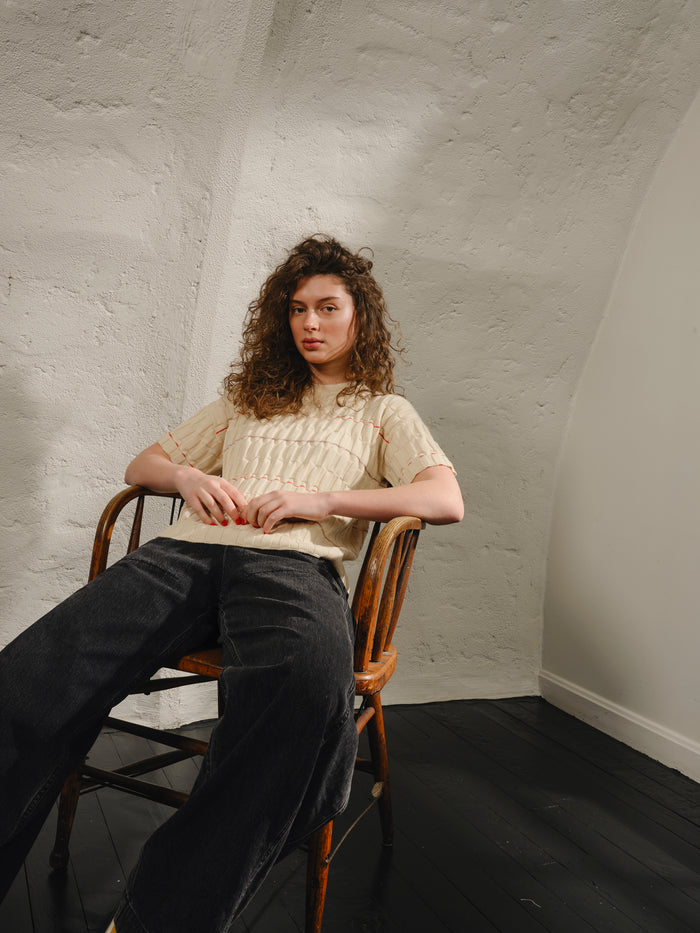 Person sitting on a chair against a white textured wall
