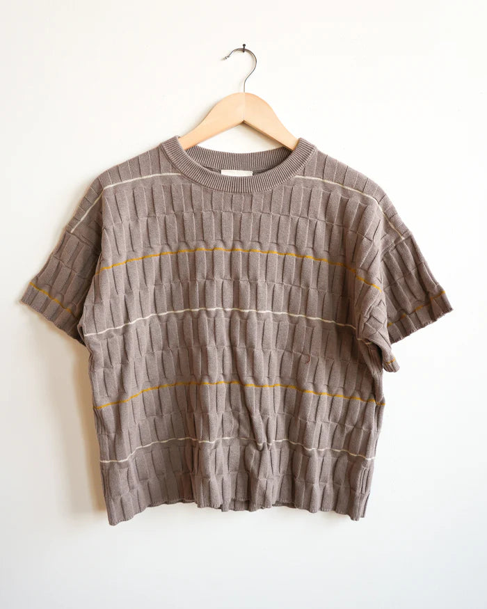 Brown ribbed sweater with yellow and white stripes on a hanger against a white background