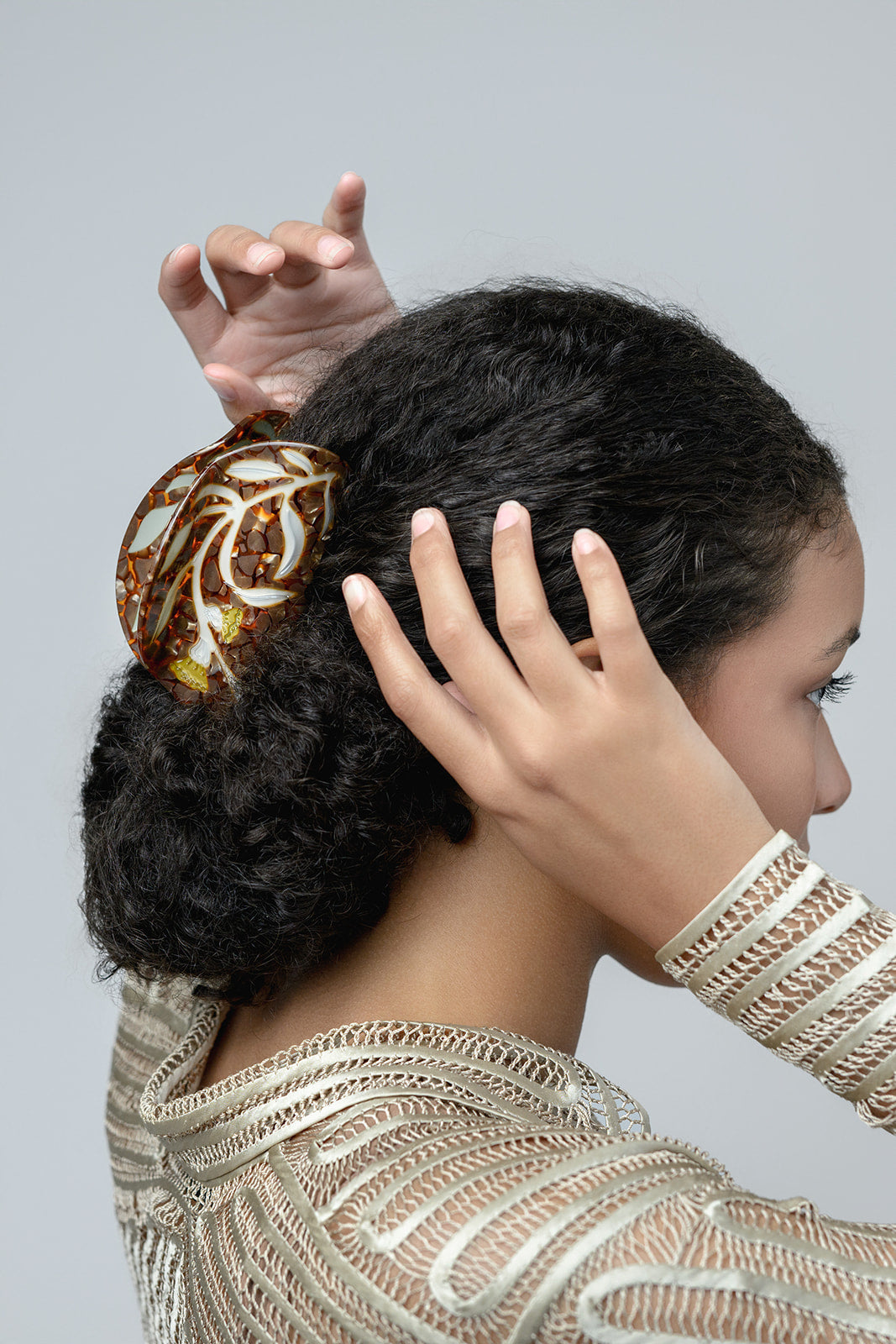 Model wearing a decorative hair clip with tortoiseshell pattern and florals.