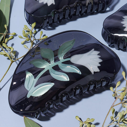 Black hair clip with floral design on a light blue background