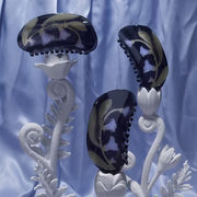 Moonflower Hair Claw with black and gold patterns on a white stand against a blue curtain background