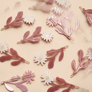 Floral and leaf-shaped hair clips on a beige background