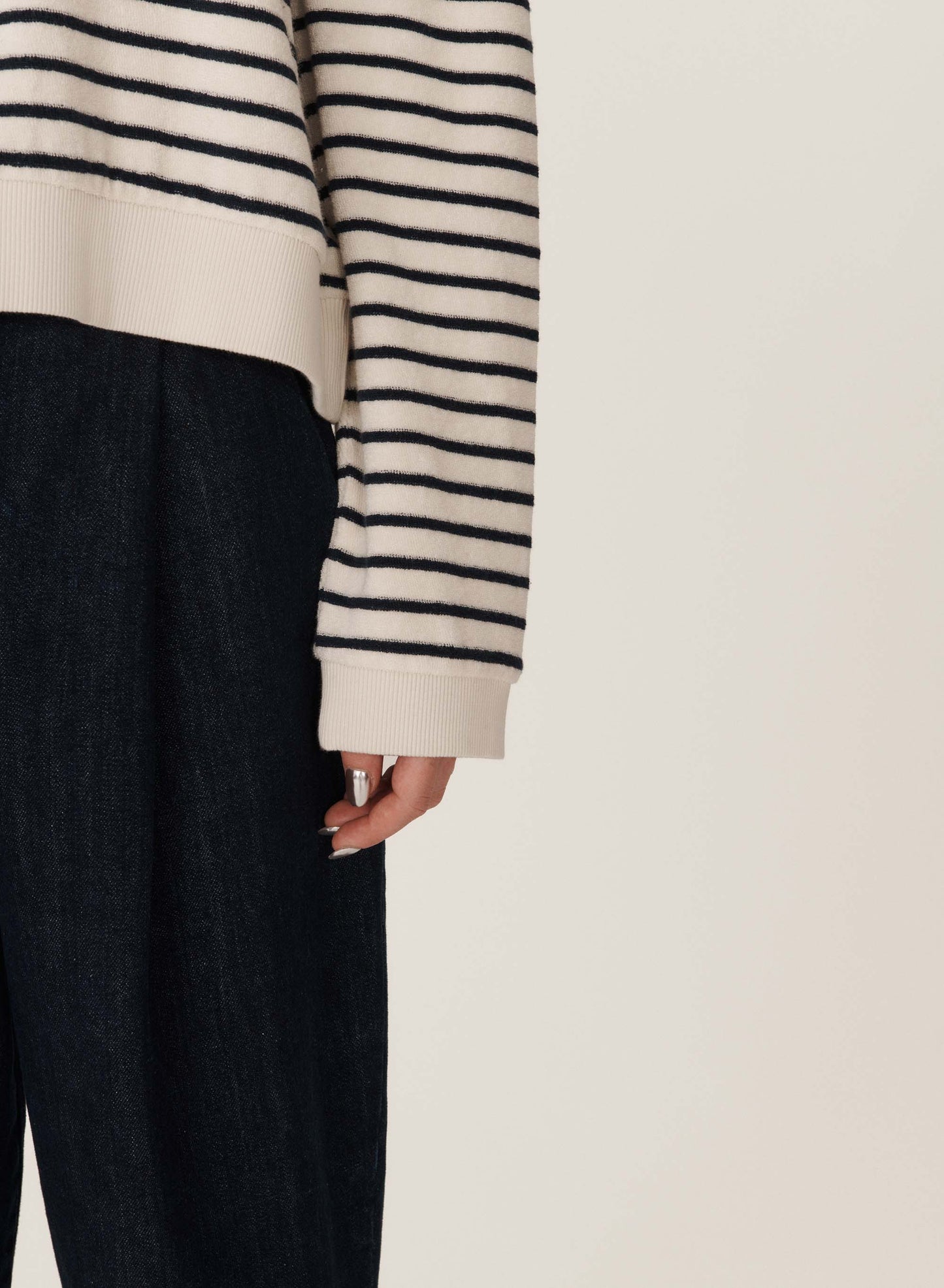 Detail of rib ecru hem and cuff. Stripe long sleeve and stripe portion of body shown. Left leg of dark navy jeans in the photo