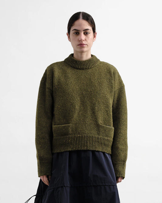 Person wearing a green knitted sweater on a white background
