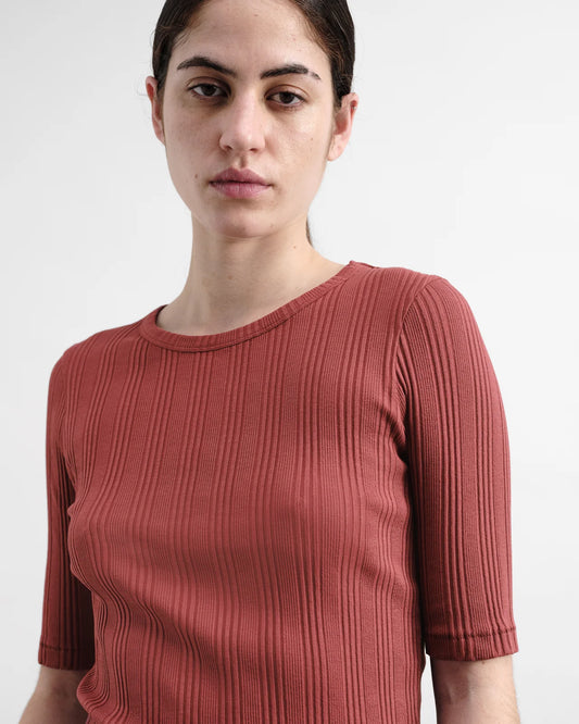 Woman wearing a ribbed burgundy top against a white background