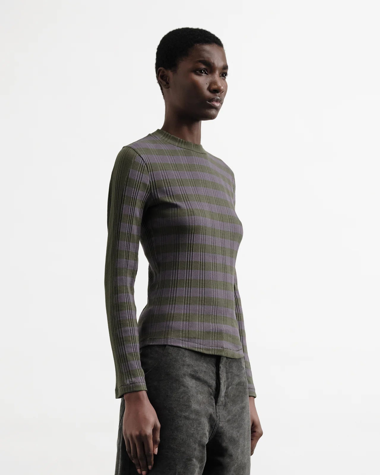 Person wearing a green and purple striped sweater on a white background