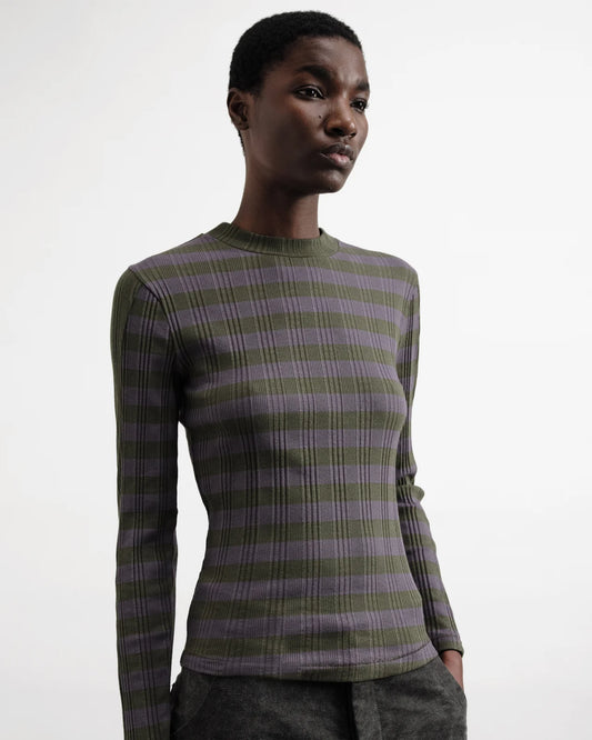 Person wearing a green and purple plaid sweater on a white background