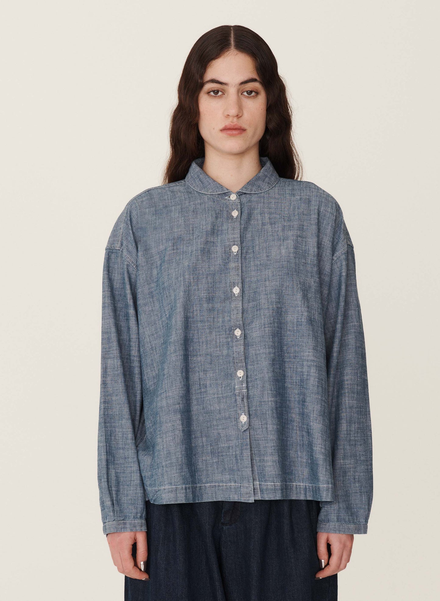 long sleeve chambray cotton front 7 buttoned shirt with rounded collar. worn over dark navy denim jeans