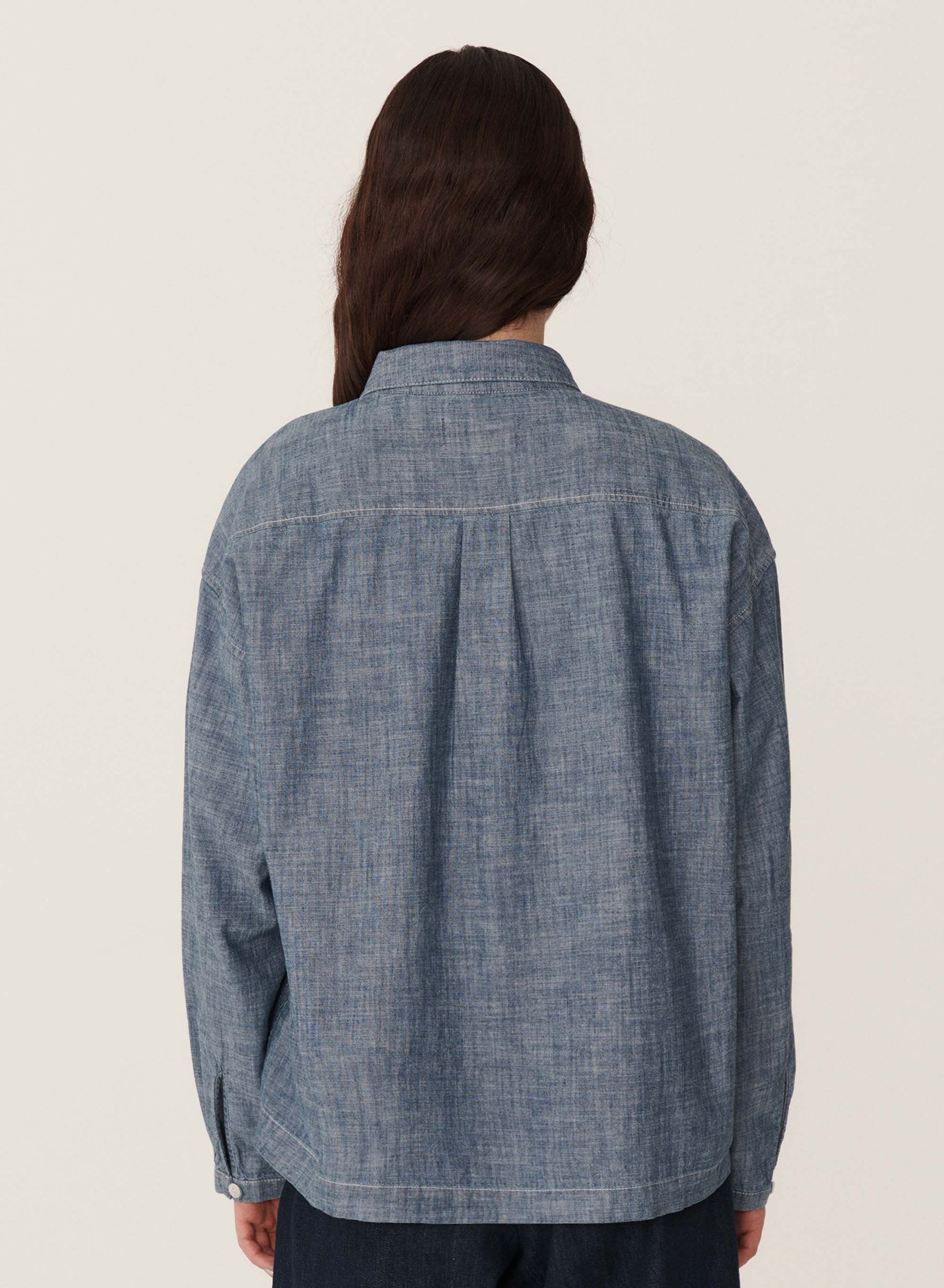 Back view of rounded collar indigo blue shirt. White stitching along all seams including pictured back yoke