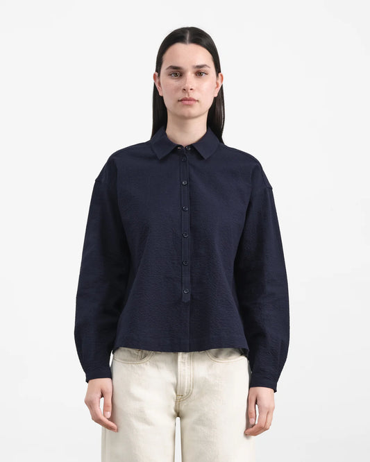 Person wearing a navy blue shirt and light-colored pants on a white background