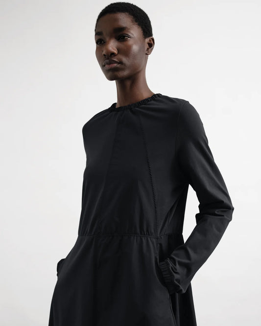Person wearing a black dress against a white background