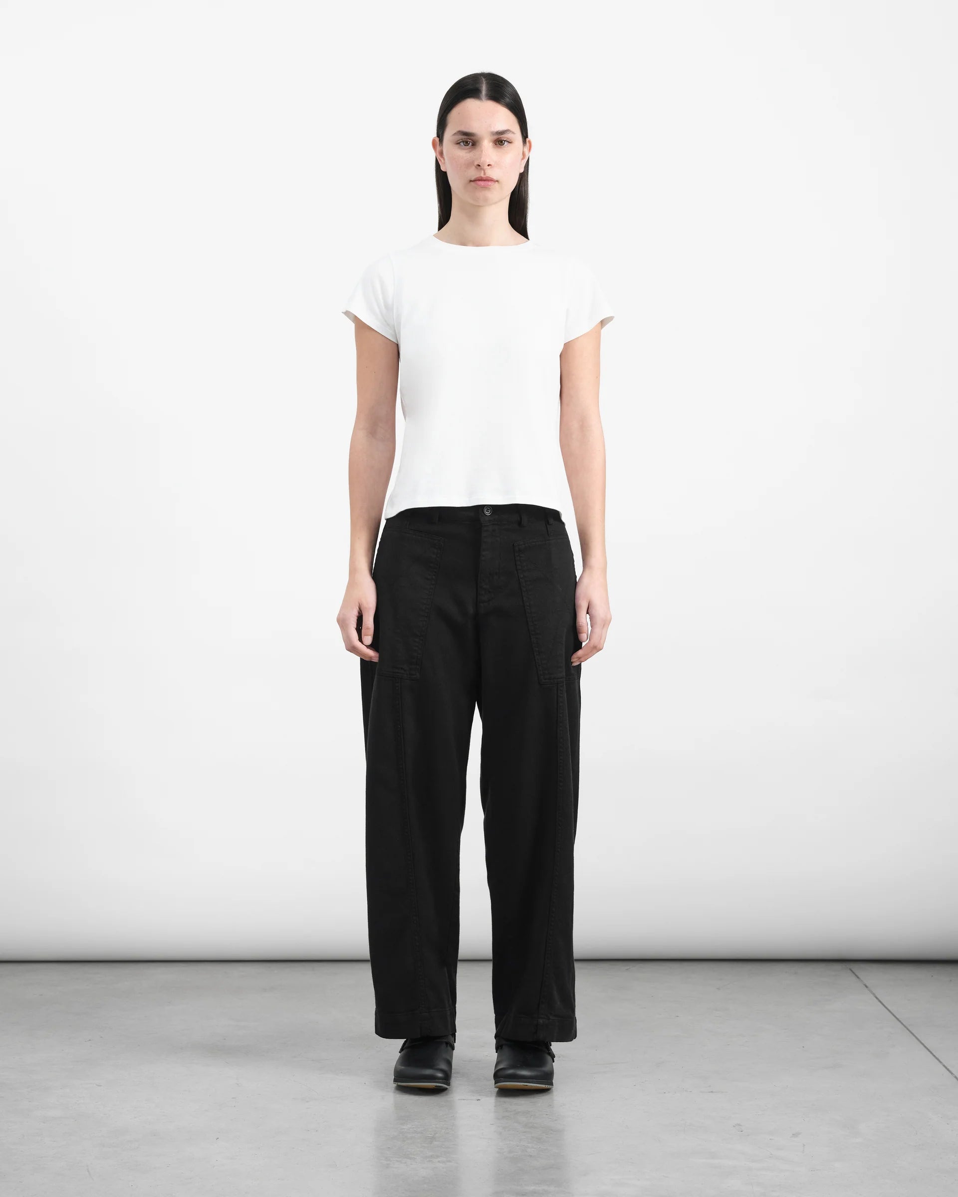 Person wearing a white t-shirt and black pants on a plain background