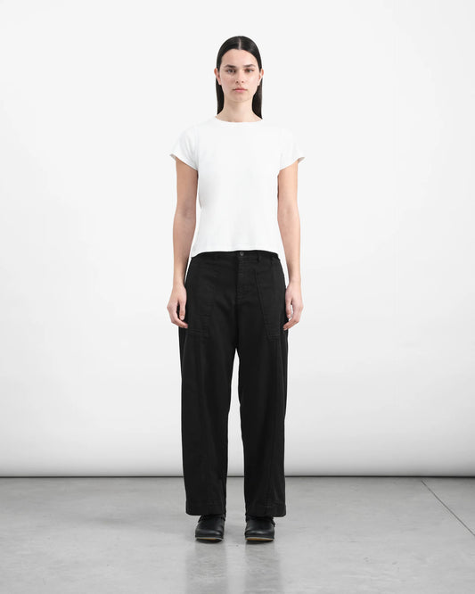 Person wearing a white t-shirt and black pants on a plain background