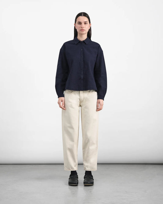 Person wearing a navy shirt and beige pants on a white background