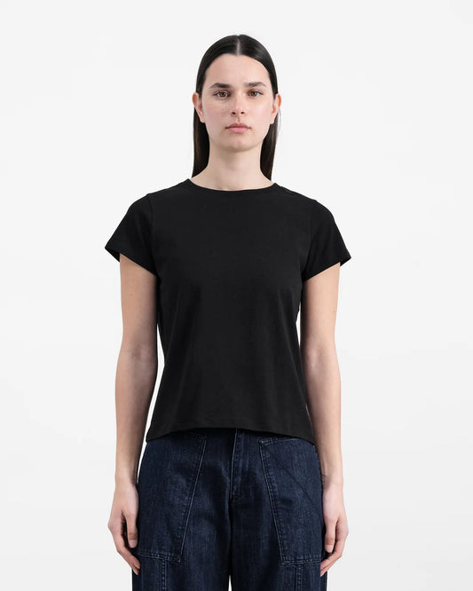 Person wearing a black t-shirt and dark jeans on a white background