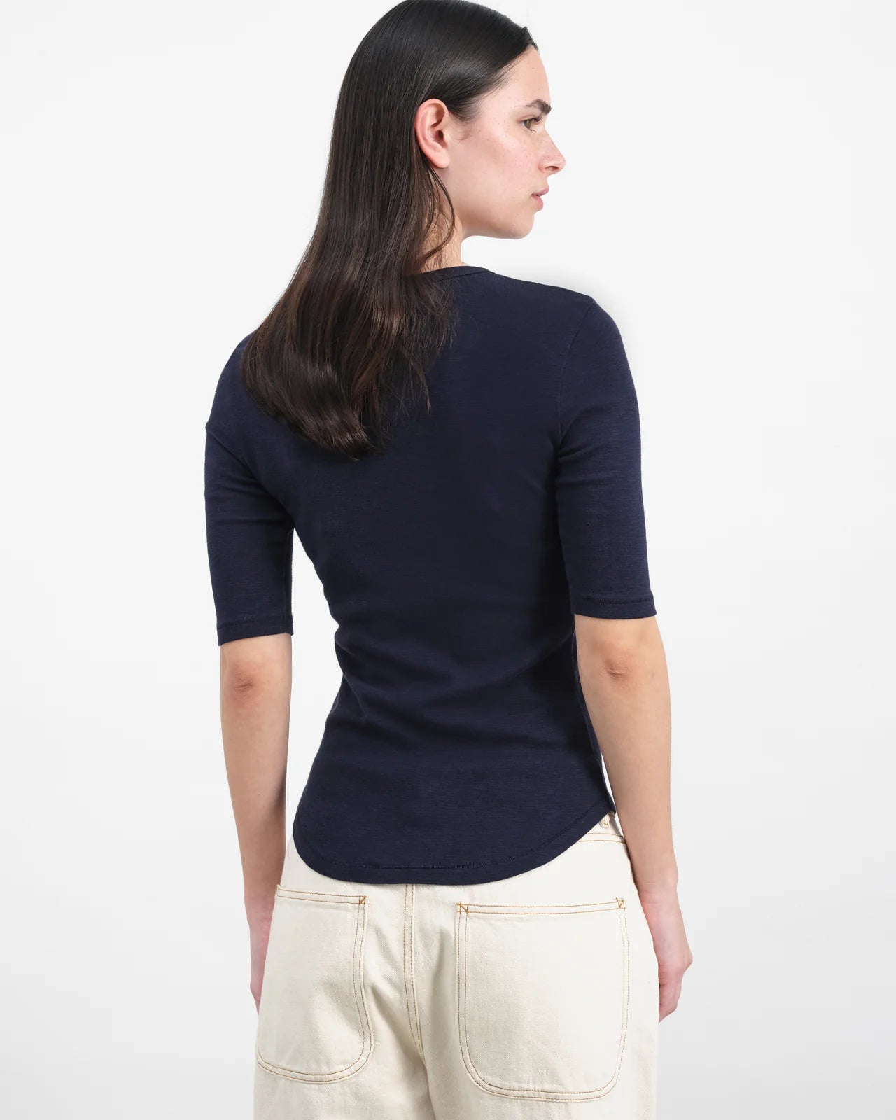 Woman wearing a navy blue top and light-colored pants on a white background