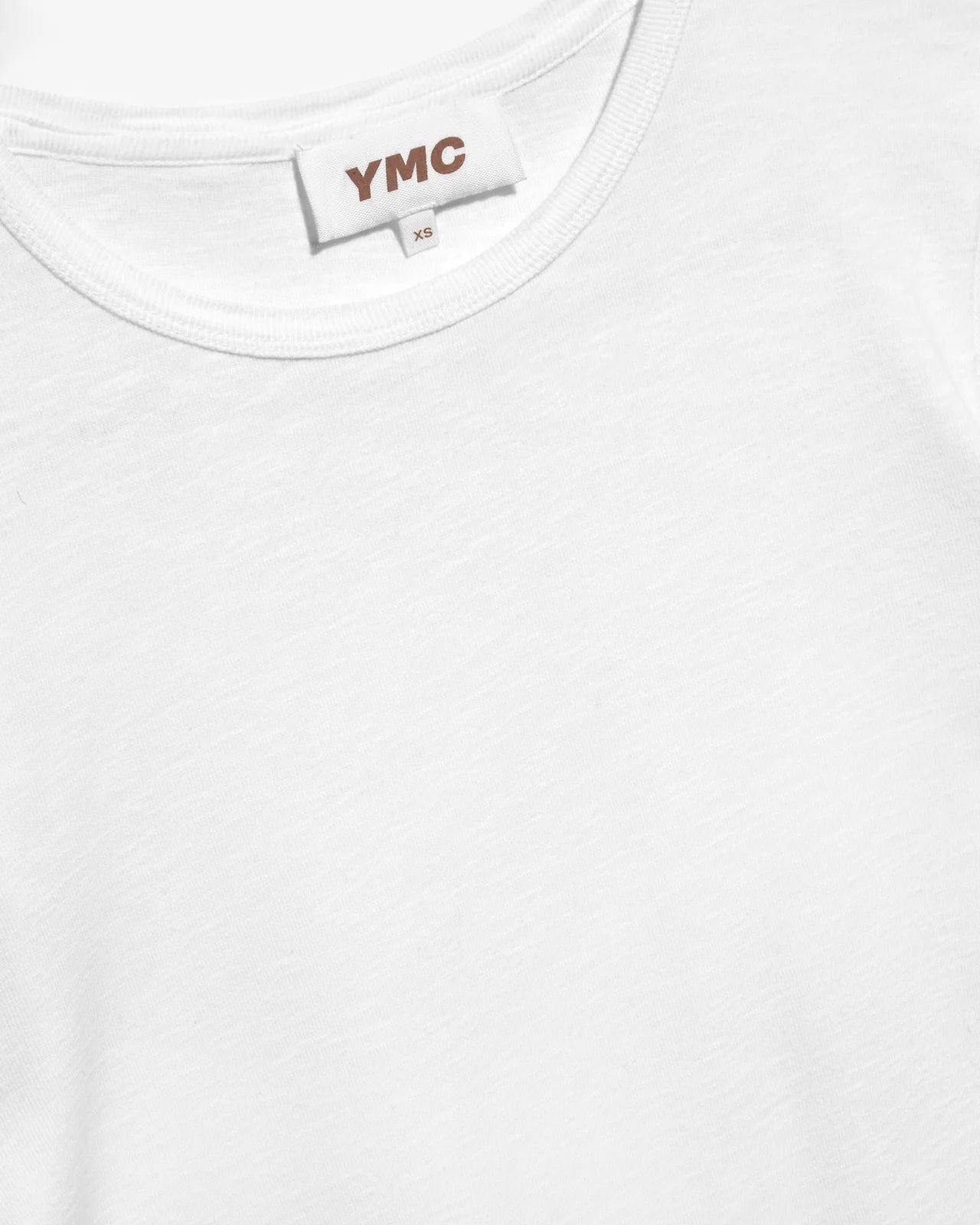 White t-shirt with 'YMC' label on a white background