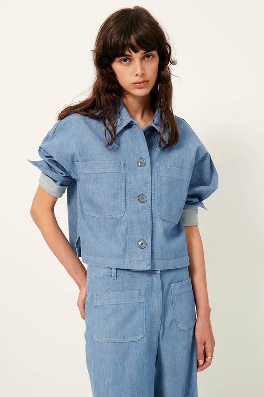 Kneee up picture of young women with long brown hair and brown eyes wearing a blue cotton shirt .