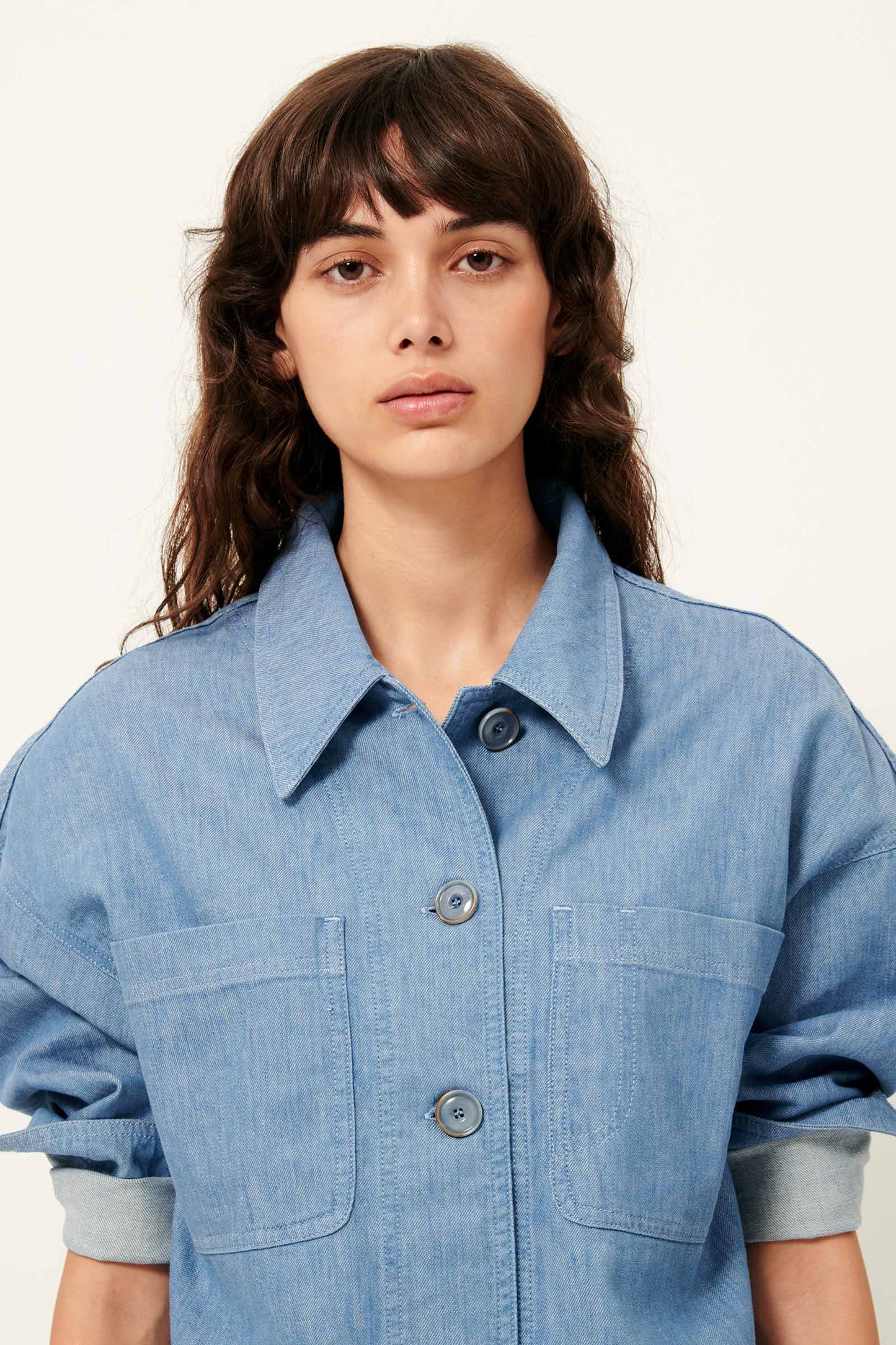 Waist up picture Young women with long brown hair and brown eyes wearing a blue cotton shirt 