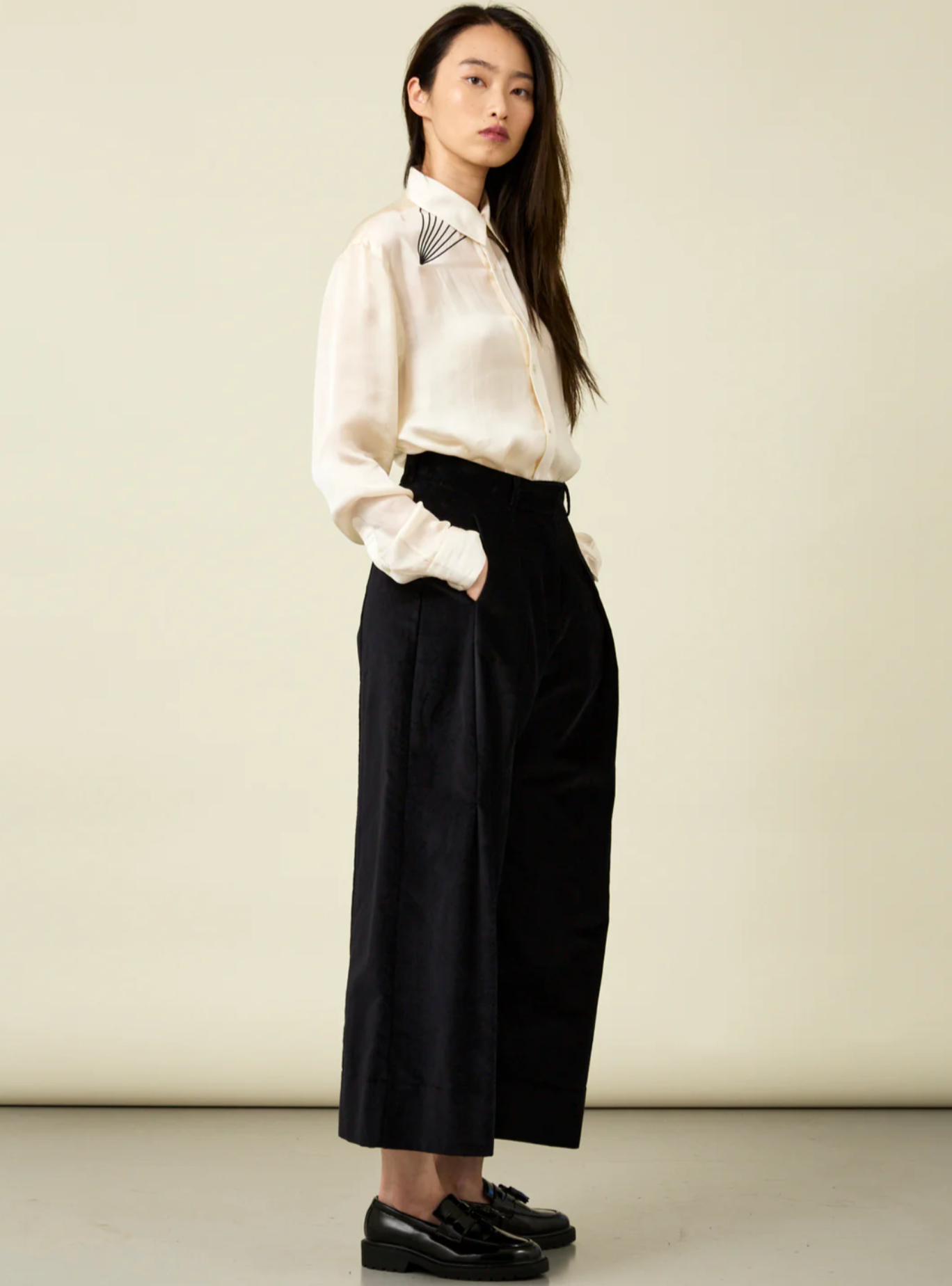 woman wearing wide leg black velvet pants with cream shirt