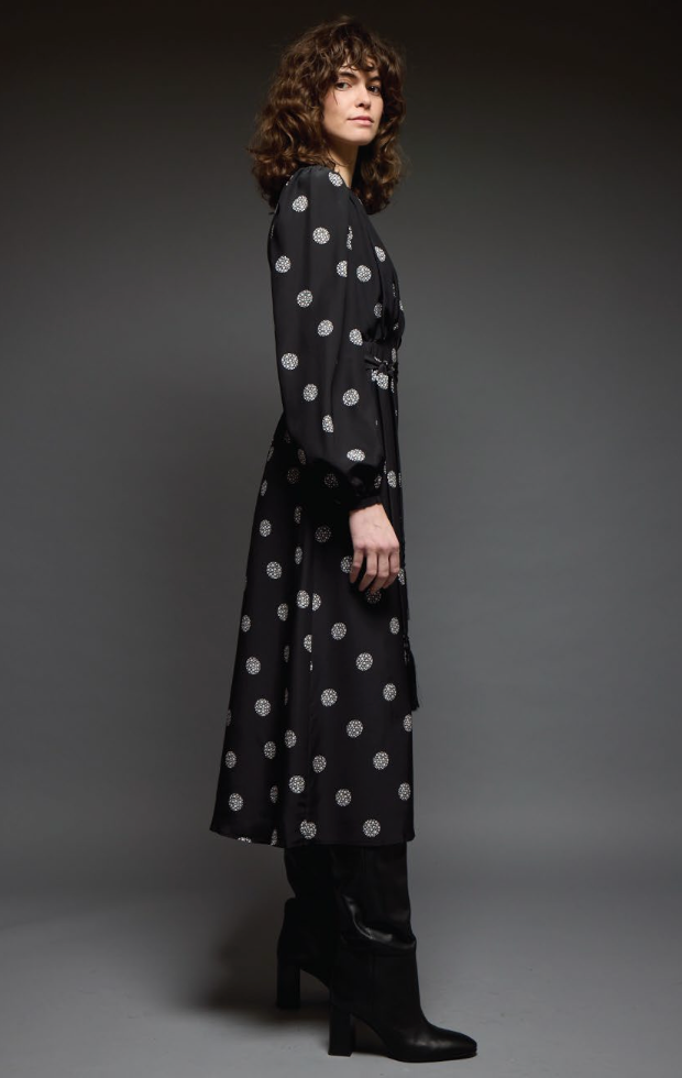 Woman wearing a black polka dot dress against a gray background