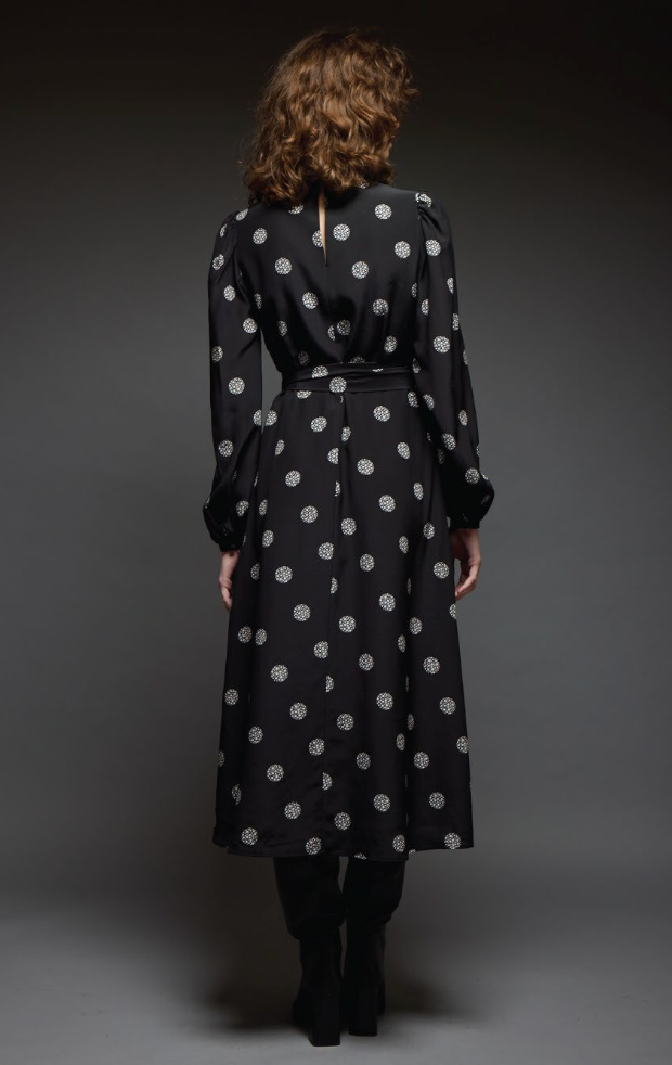 Woman wearing a black dress with white polka dots from behind on a dark background
