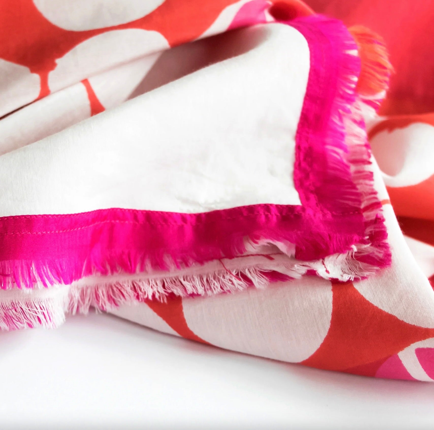Close-up of a red, white, and pink patterned fabric with frayed edges.