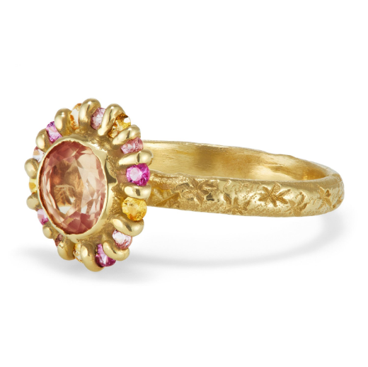 side view of gold ring with a faceted peach color sapphire surrounded by smaller yellow, pink and orange sapphires.