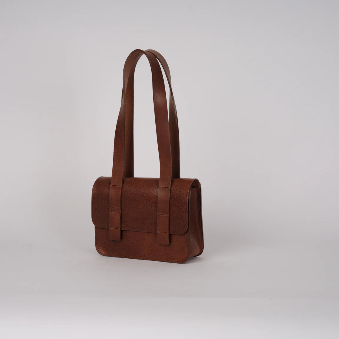 Brown leather handbag on a light gray background