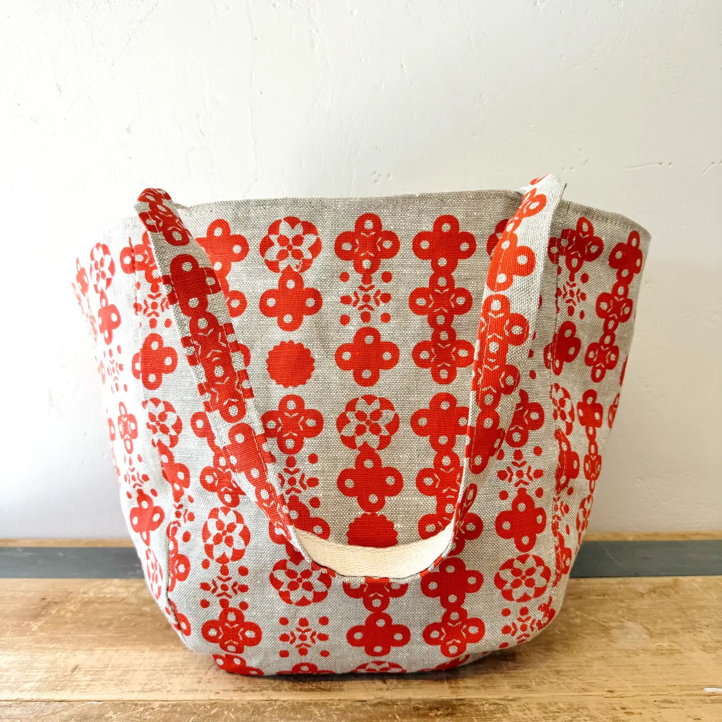 Red floral patterned bag on a wooden surface with a white background