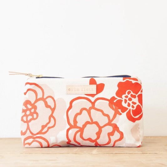 Floral patterned pouch with a visible brand label on a wooden surface.