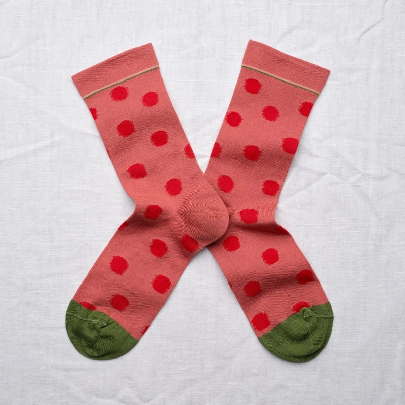 Red polka dot socks with green toes and heels on a white background