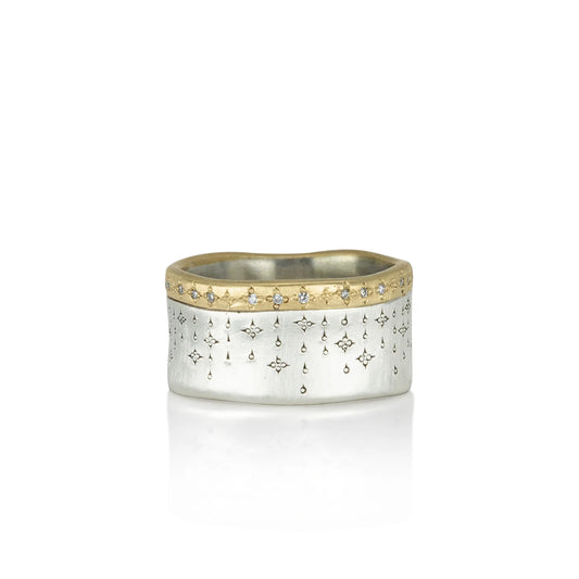 Silver ring with gold accents and star designs on a white background